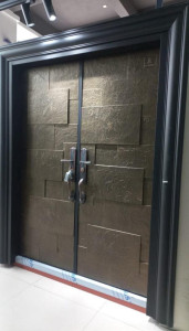 Bronze or gold-coloured steel Security Door with a textured stone-like finish and modern handles