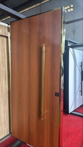 Modern Flush Wooden Door with Prominent Vertical brass-coloured pull handle and matching trim