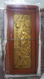 Wooden door with an ornate gold relief panel featuring cranes and foliage