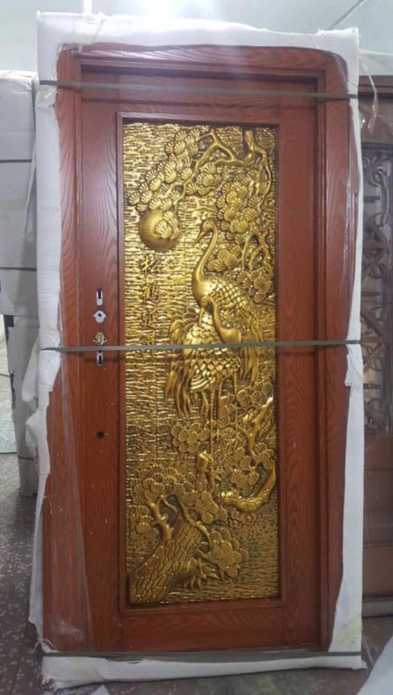 Wooden door with an ornate gold relief panel featuring cranes and foliage