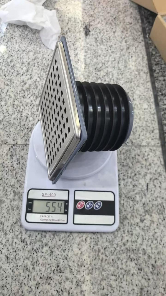 Square shower floor drain with a removable grate and flexible pipe trap