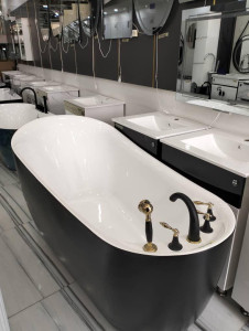 White freestanding acrylic bathtub with black and gold vintage-style faucets